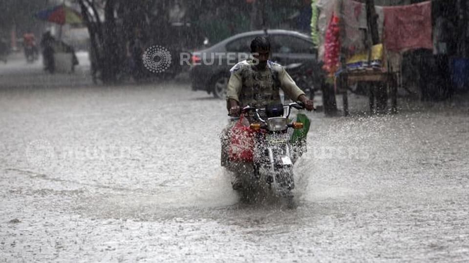 um che va cun moped tras via inundada a pakistan