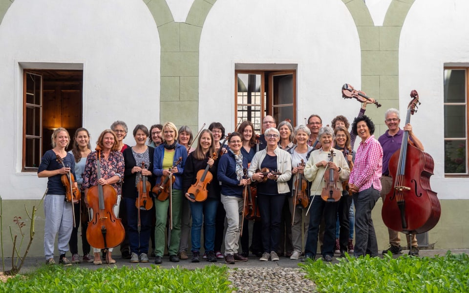 Musikerinnen und Musiker der Orchestrina stehen vor einem Haus