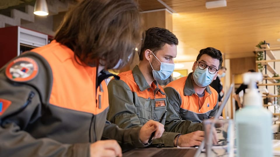 Ina comembra e dus comembers da la protecziun civila discussiunan ensemen