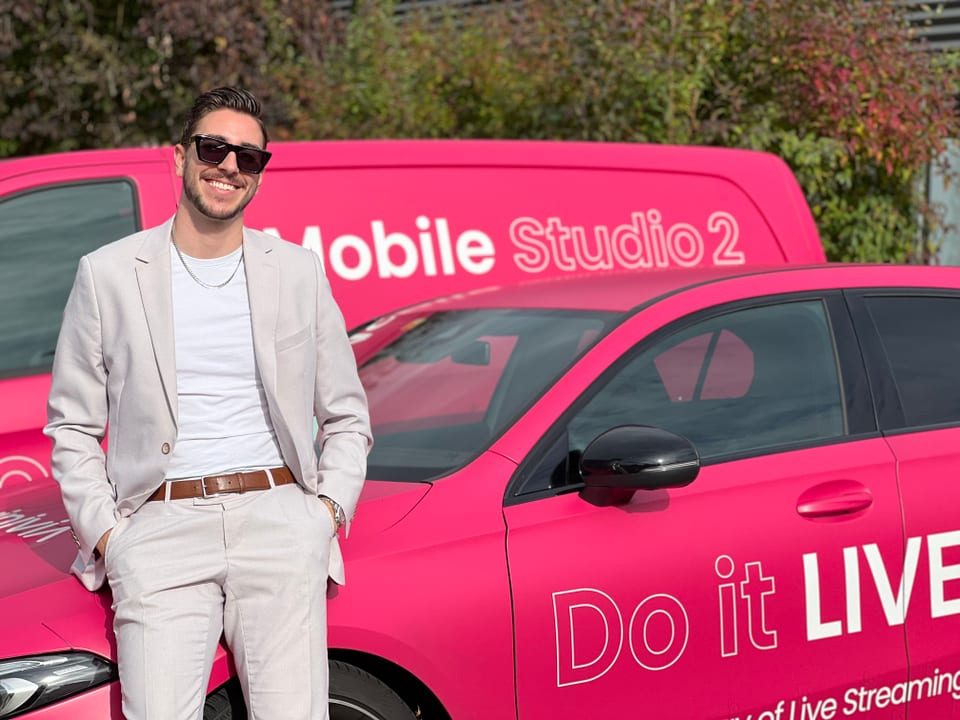 Gian-Andrea vor dem pinkigen Auto seiner Firma.
