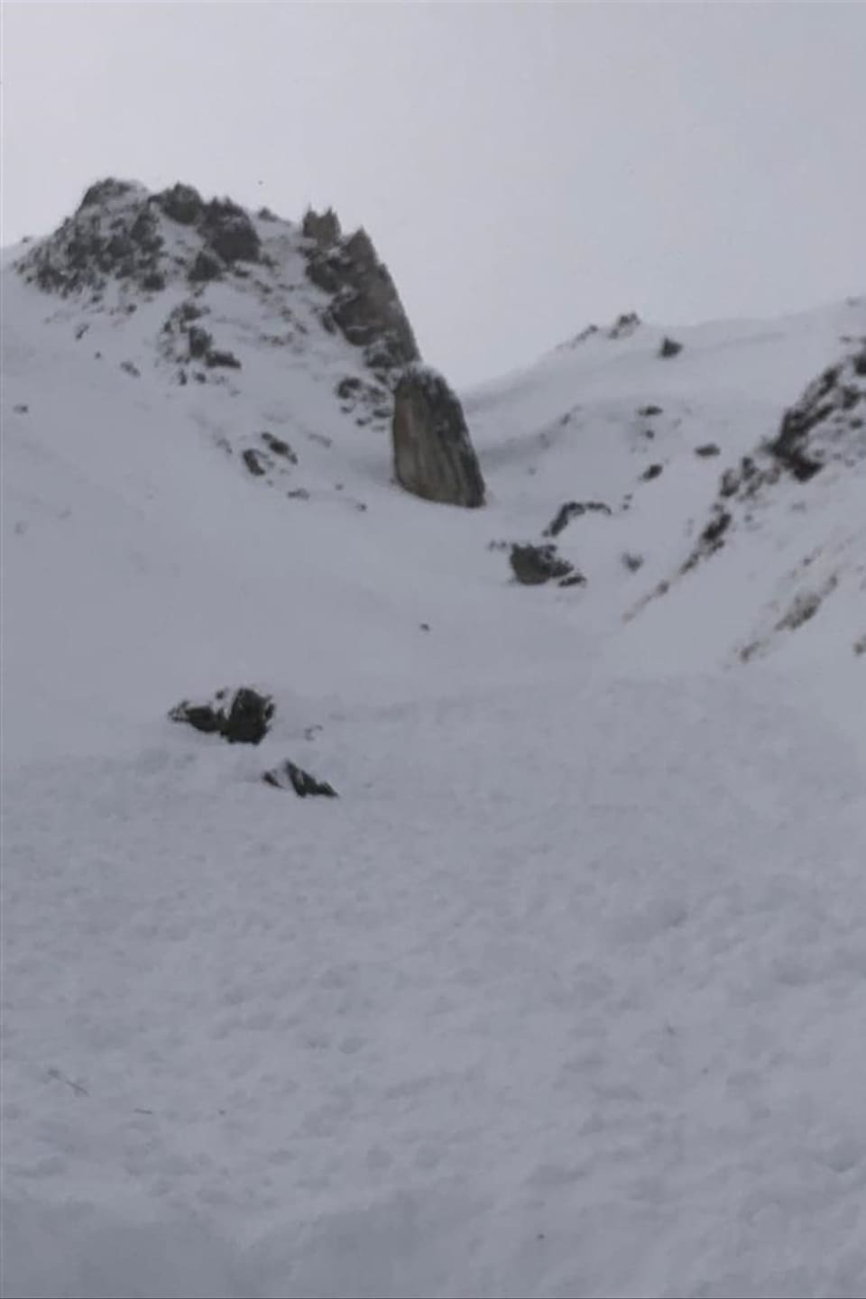 Lawinenabgang mit Felsen im Hintergrund