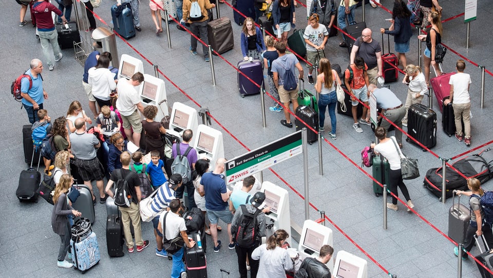 Passagiers vid il far il check-in a l'eroport da Turitg. 