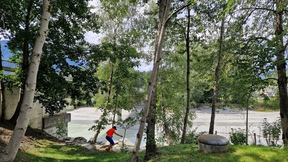 Eine Frau rennt durch Bäume entlang eines Flusses.