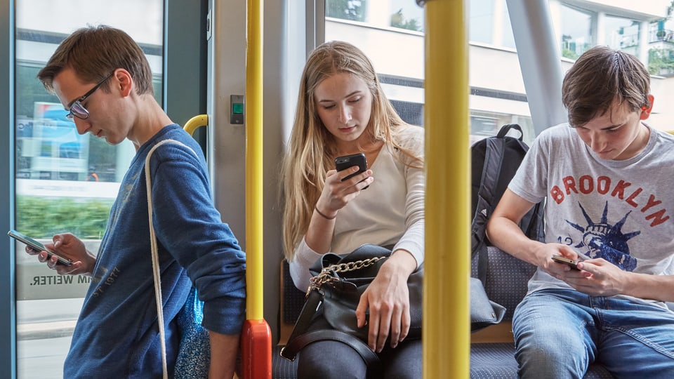 Giuvenils cun telefonin en in bus u tram. 