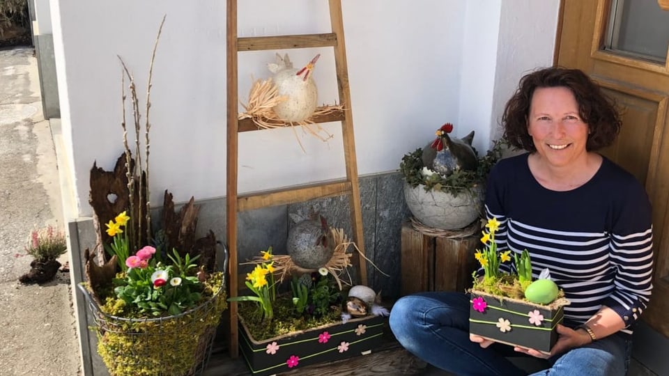Carmelia Casanova avant isch-chasa Carmelia Casanova sitzt vor der Haustüre mit Blumen in der Hand.