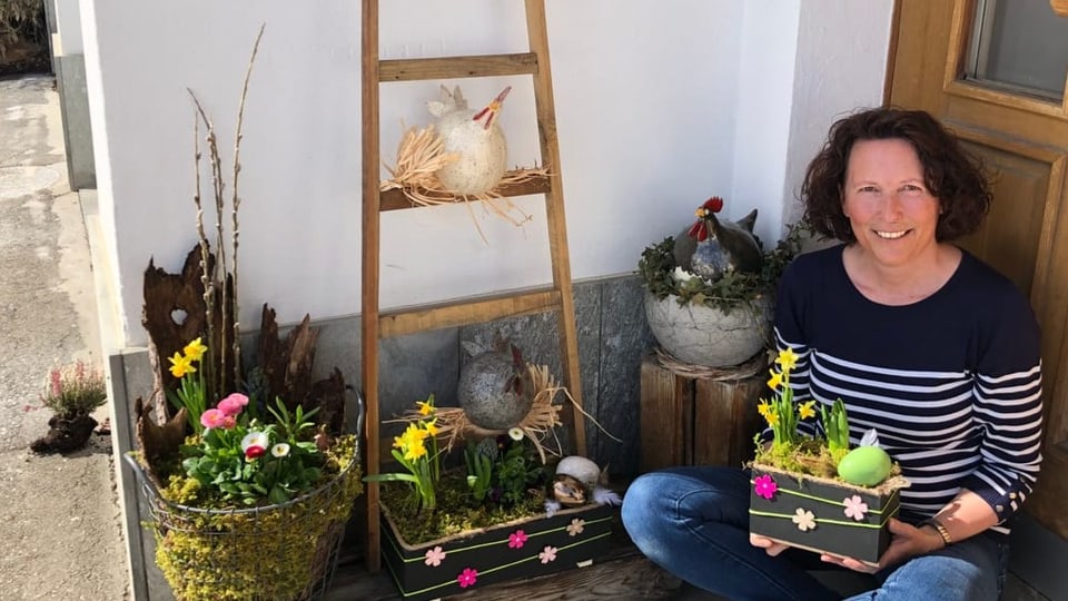 Carmelia Casanova sitzt vor der Haustüre mit Blumen in der Hand.