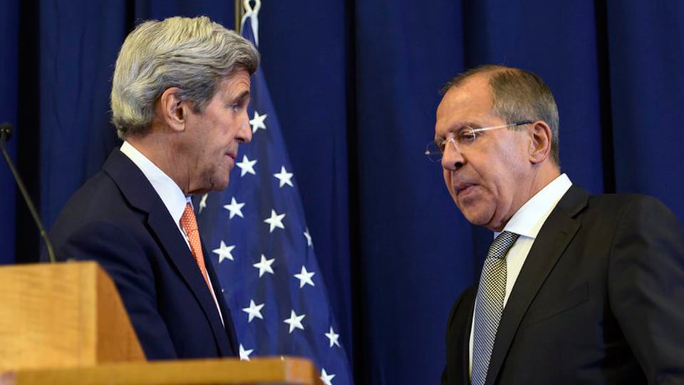 John Kerry e Sergej Lawrow davant in vel blau. Davos John Kerry e vesaivel ina bandiera dals stadis Unids