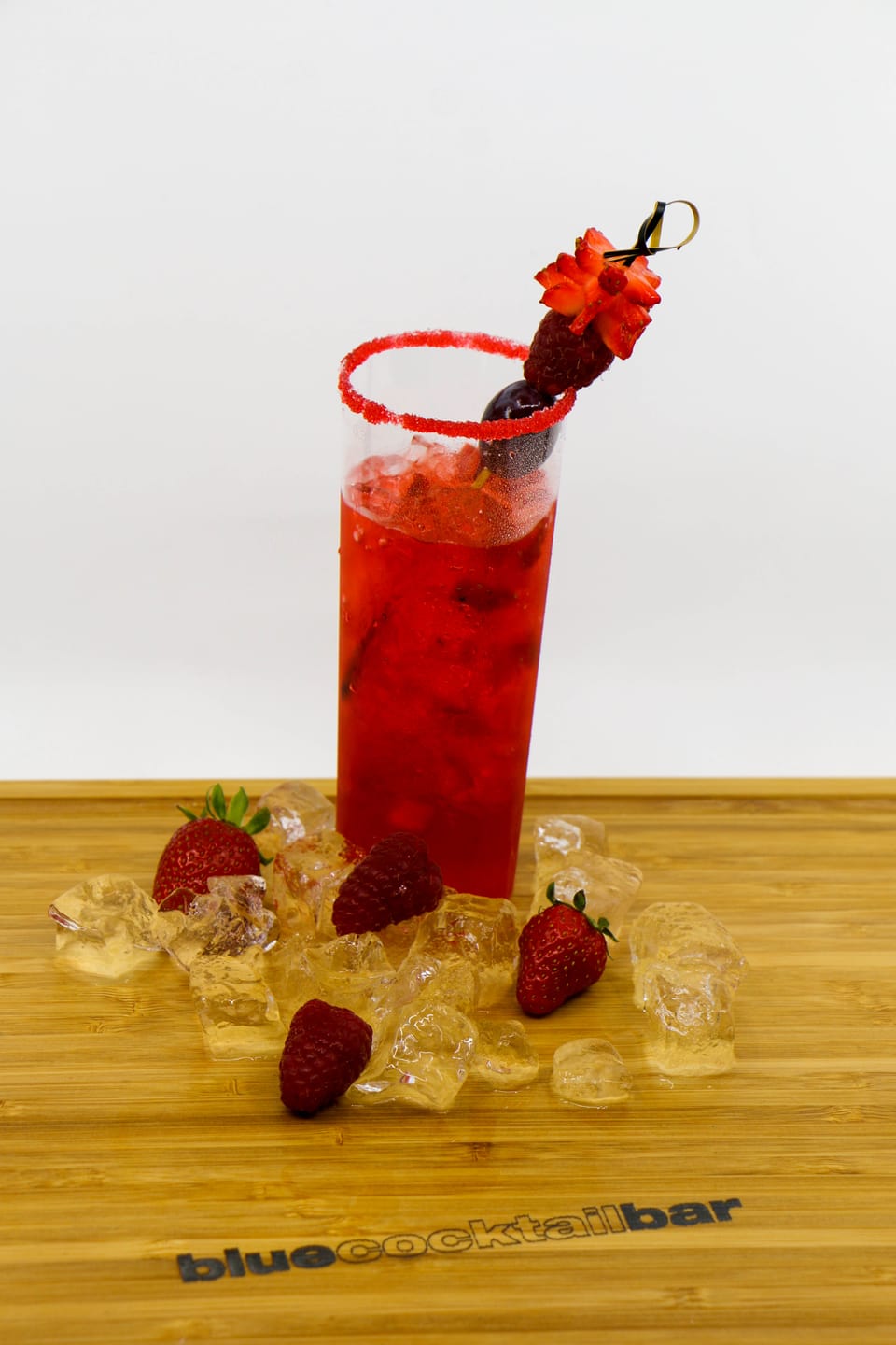 roter Cocktail mit Zuckerrand, dekoriert mit Beeren