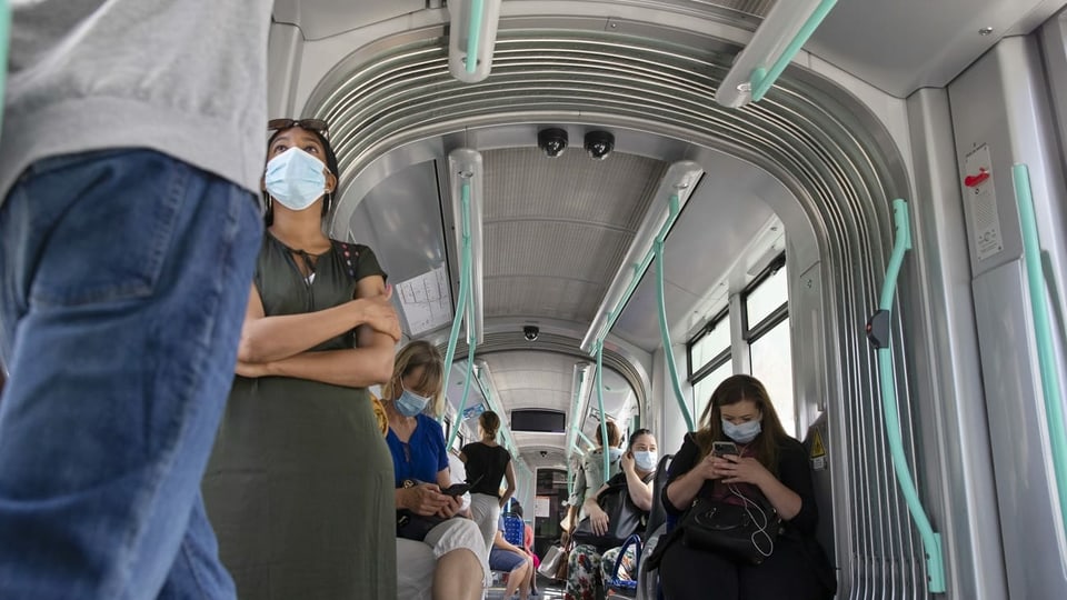Purtret da persunas che portan mascras en il traffic public. 
