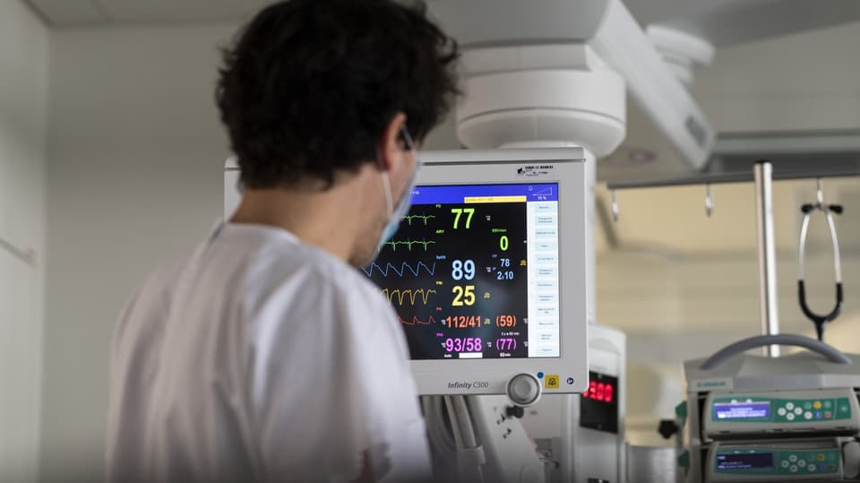 Eine Pflegerin arbeitet in der Intensivstation eines Spitals an einem Monitor mit komischen Grafiken und Zahlen drauf.