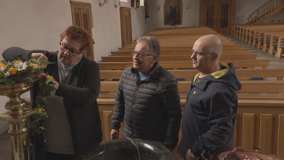 Eine Frau und zwei Männer im Gespräch in der Kirche