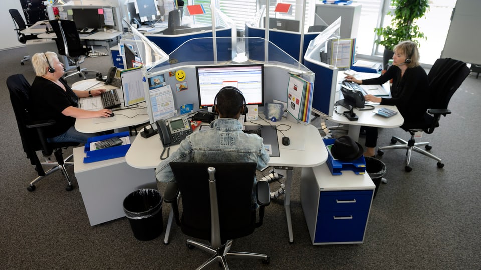 Biro cun trais persunas che lavuran vid computers.