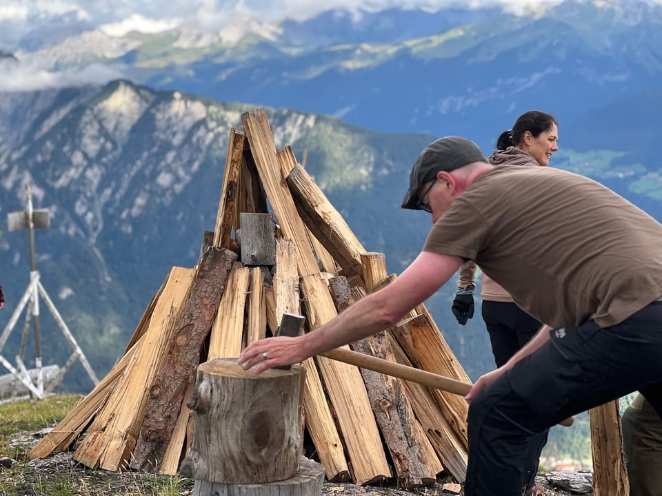 Ein Mann hackt Holz für ein Höhenfeuer.