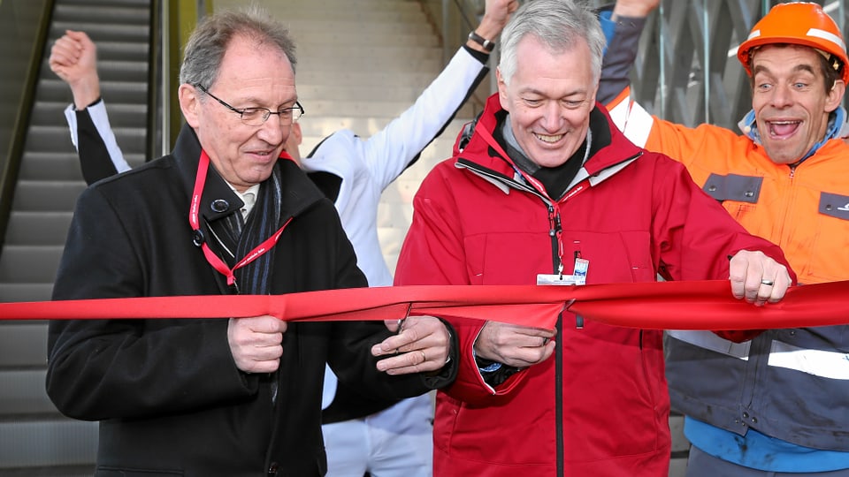 Il directur da la RhB Hans Amacker (dretg) e Lorenza Schmid, president communal d’Arosa, taglian tras la fascha cotschna ed inaugureschan uschia la nova passarella.