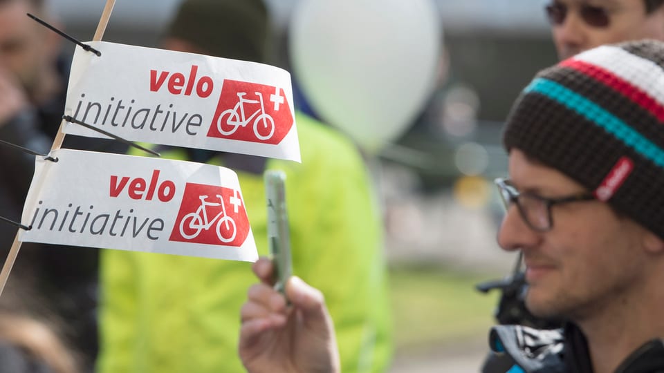 Um e duas bandierinas cun scrit si «velo-initiative».