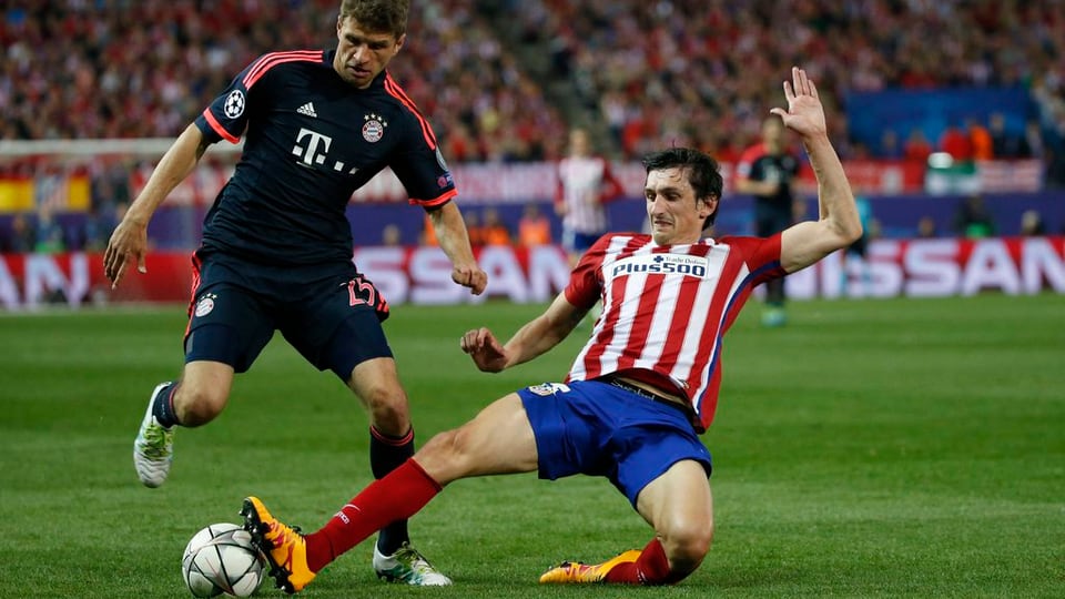 L'attatgader Müller (san.) da Bayern München cunter il defensur Savic (dre.) entamez l'acziun.