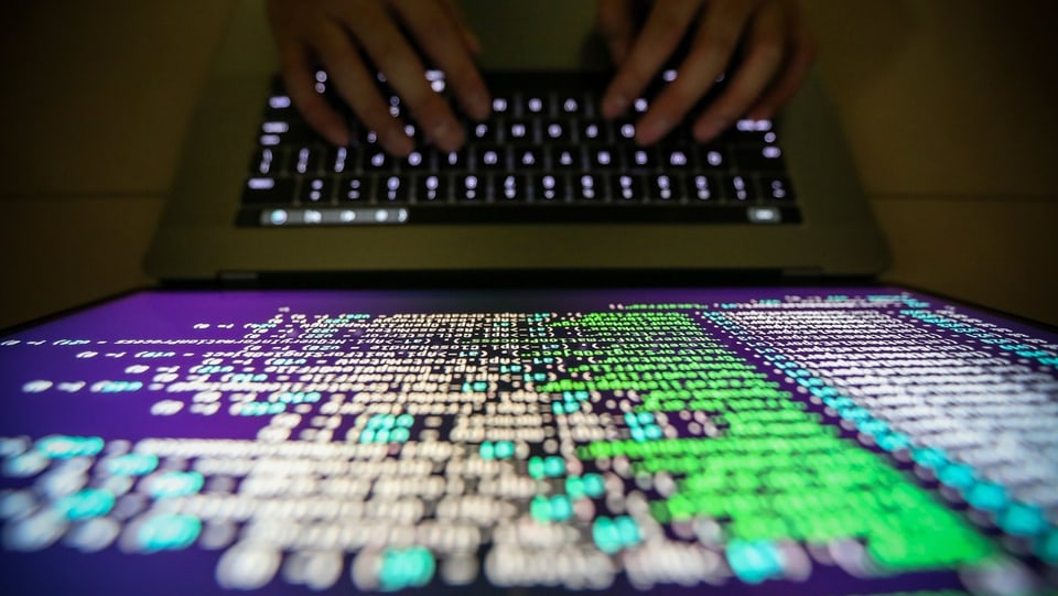 Purtret d'in computer e mauns che scrivan sin la tastatura. 