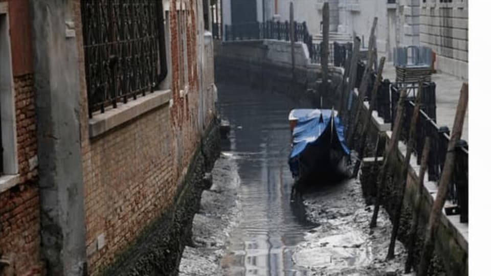 Ina gondola en in dals chanals da Venezia, durant ina fitg bassa mar bassa il favrer