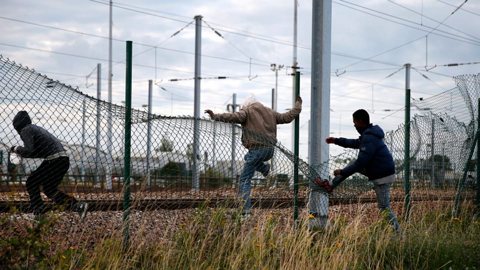 trais giuvens stgarpan giu ina saiv da fier per entrar en l'areal da l'Eurotunnel a Calais