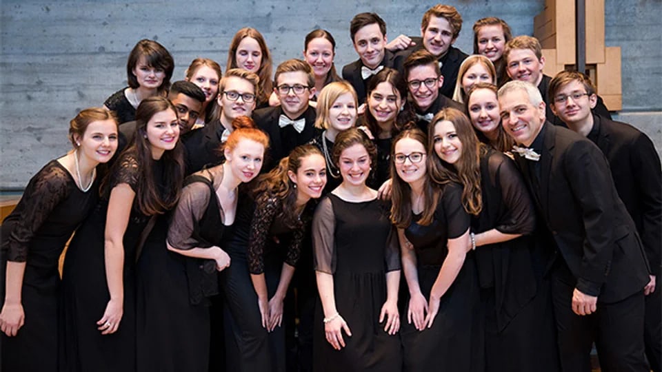 ein Jugendchor ganz in schwarz posiert für eine Fotografie