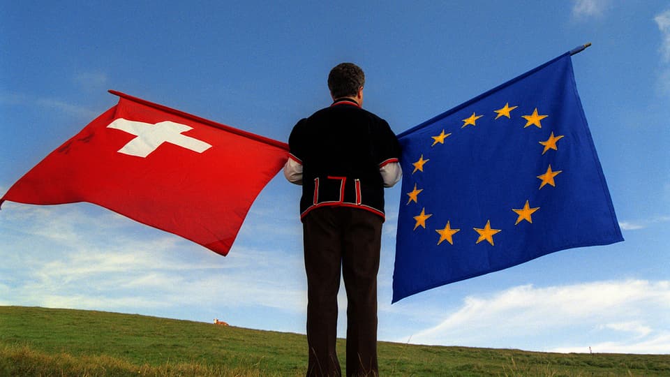 Ina bandiera da la Svizra e da l'autra vart ina da l'UE. 