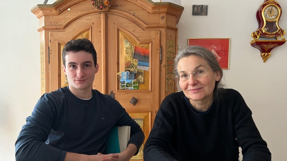 Marc Solèr cun sia mamma Der junge Bursche sitzt neben seiner Mutter am Tisch..
