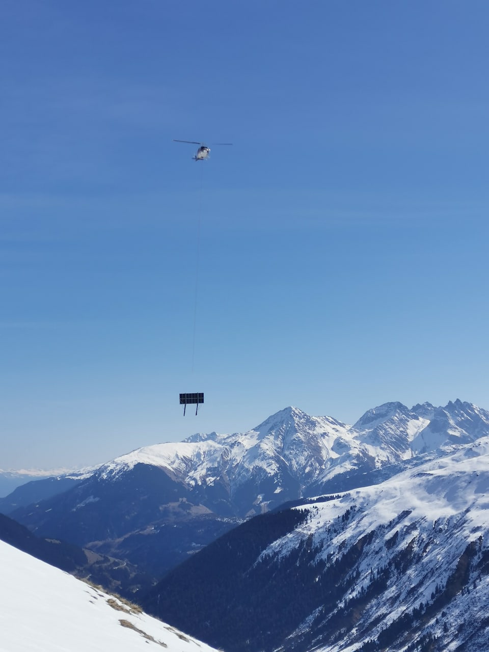 Solarpanel wird in Sedrun mit dem Helikopter transportiert.  