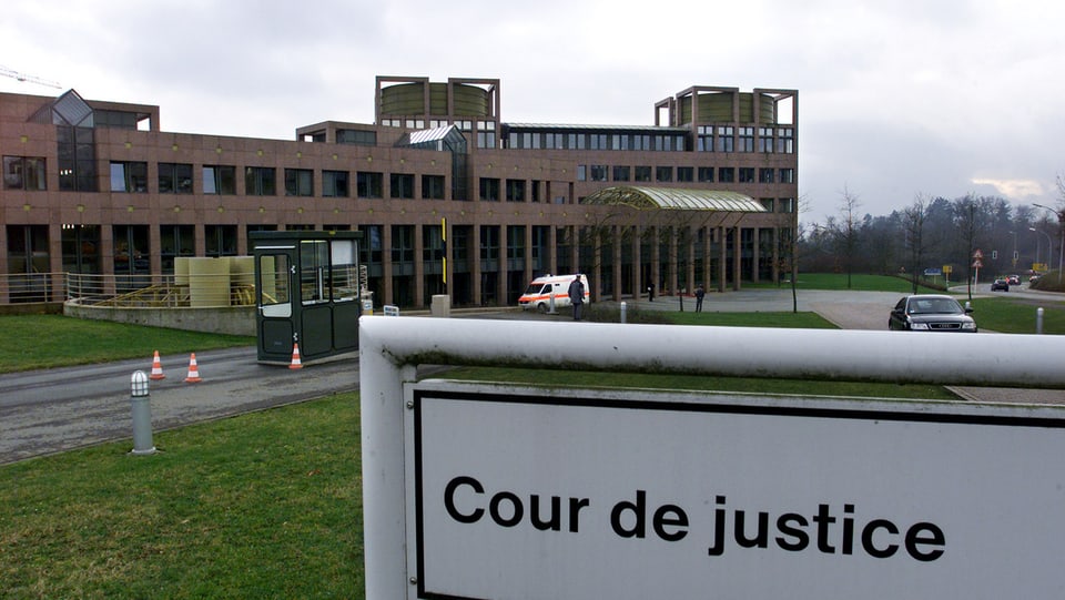 bajetg da dertgira, davant ina tavla cun l'inscripziun "cour de justice"