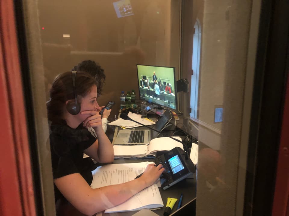 Übersetzerinnen bei der Arbeit. Mit Kopfhörern, Skript und Fernsehbildschirm.