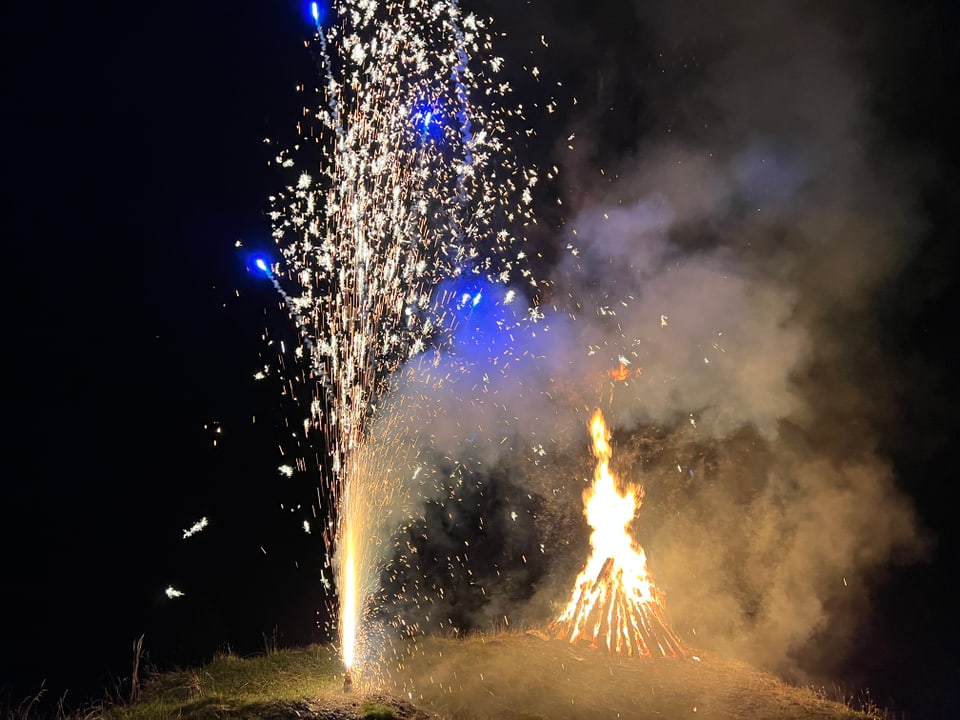 Ein Feuerwerksvulkan glüht vor dem Höhenfeuer im Dunkeln.