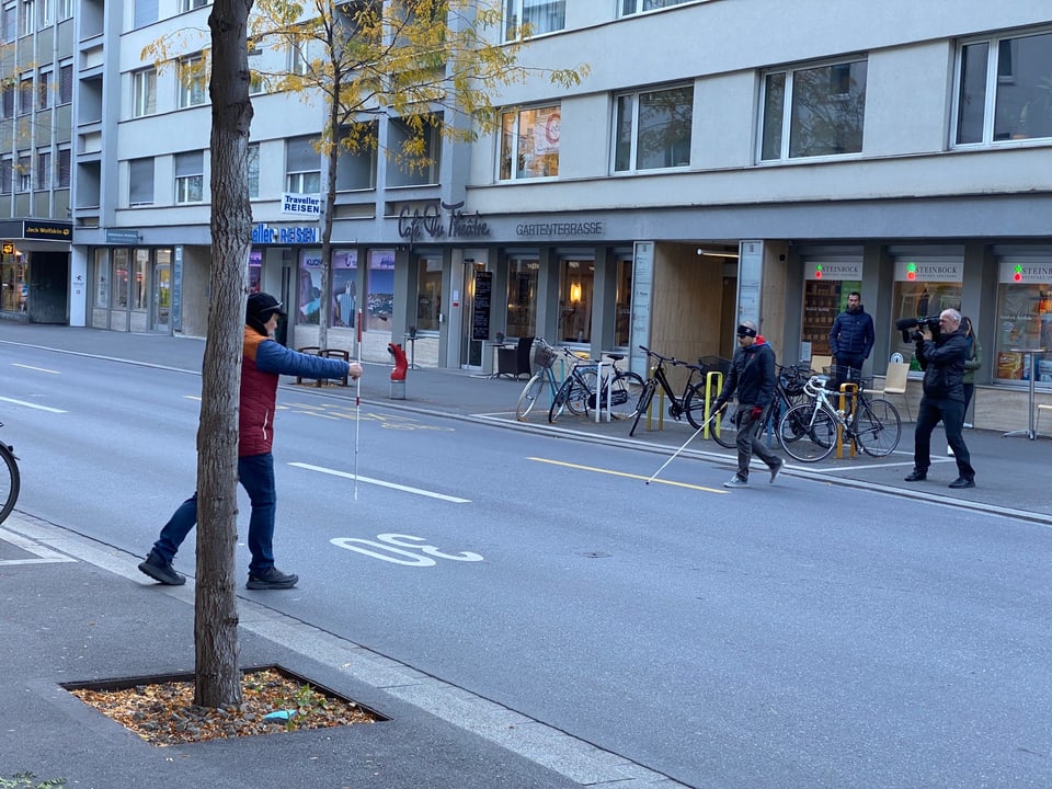 dus umens cun channas alvas traversan ina via en la zona 30