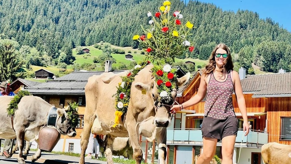 Junge Frau mit Kuh und Blumenschmuck in Brigels 