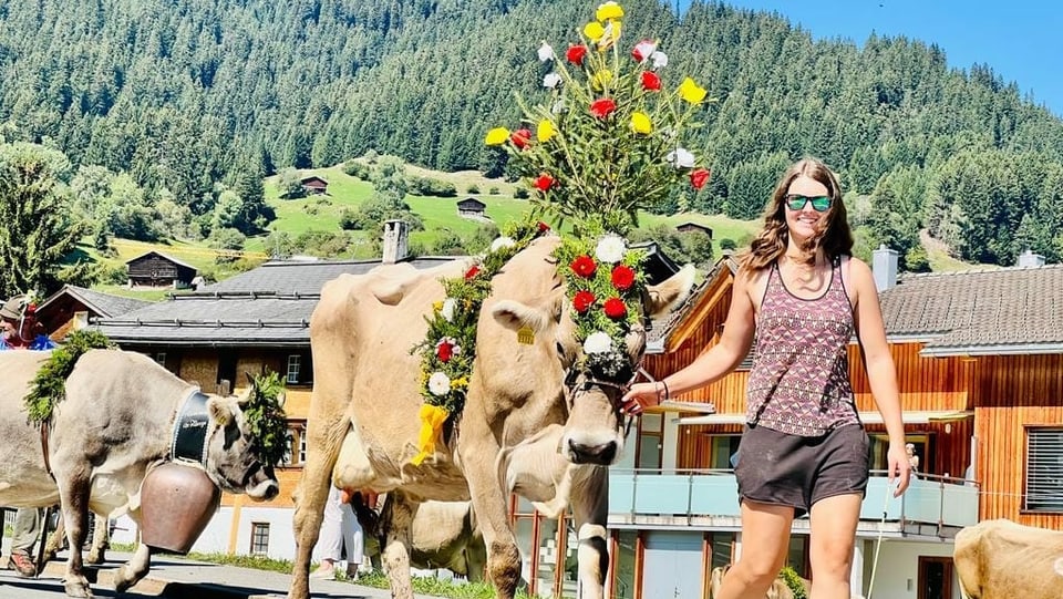 Junge Frau mit Kuh und Blumenschmuck in Brigels
