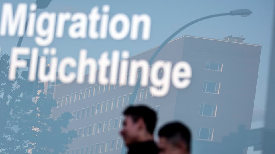 Purtret cun funs blau grisch e scrit si davant «Migration Flüchtlinge». 