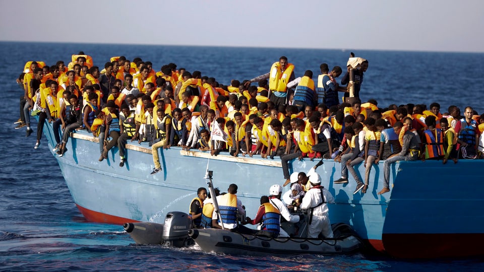 Ina bartga surchargiada cun passà 700 fugitivs sin la Mar Mediterrana. Els vegnan spindrads da gidanters talians.