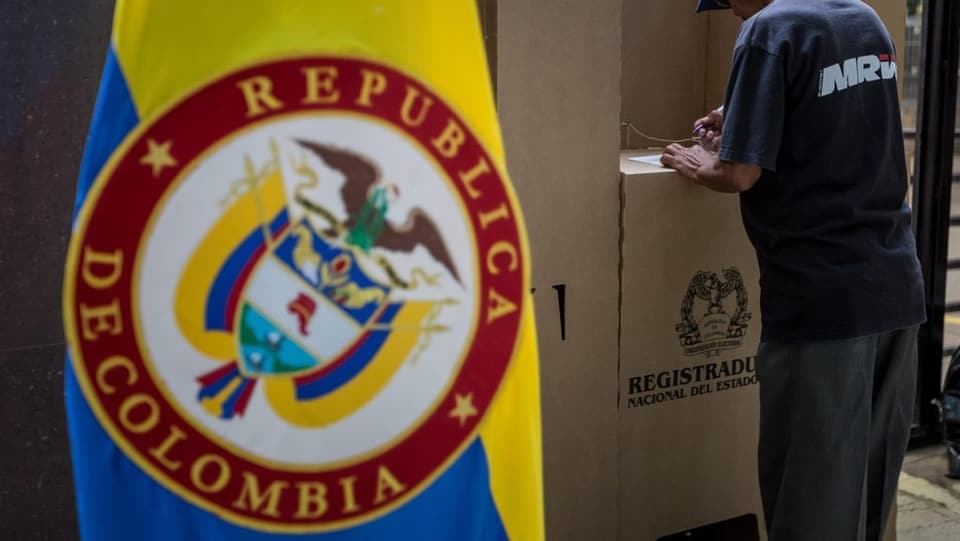 Purtret d'ina bandiera da la Columbia ed in um ch'emplaina il cedel da votaziun. 