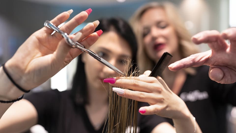 Zwei Frauen schneiden einem Kunden die Haare