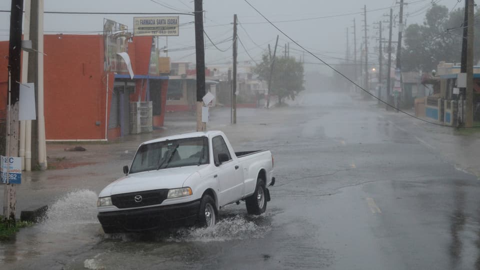 malaura ed inundaziuns en la Caribica, in auto charrescha en l'aua