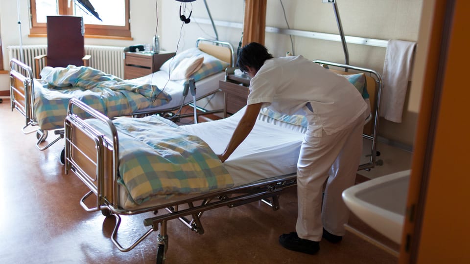 Ina tgirunza prepara in letg da spital en ina chombra cun plirs letgs