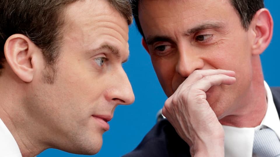 Purtret da Emmanuel Macron e Manuel Vals che scuttinan insatge. 