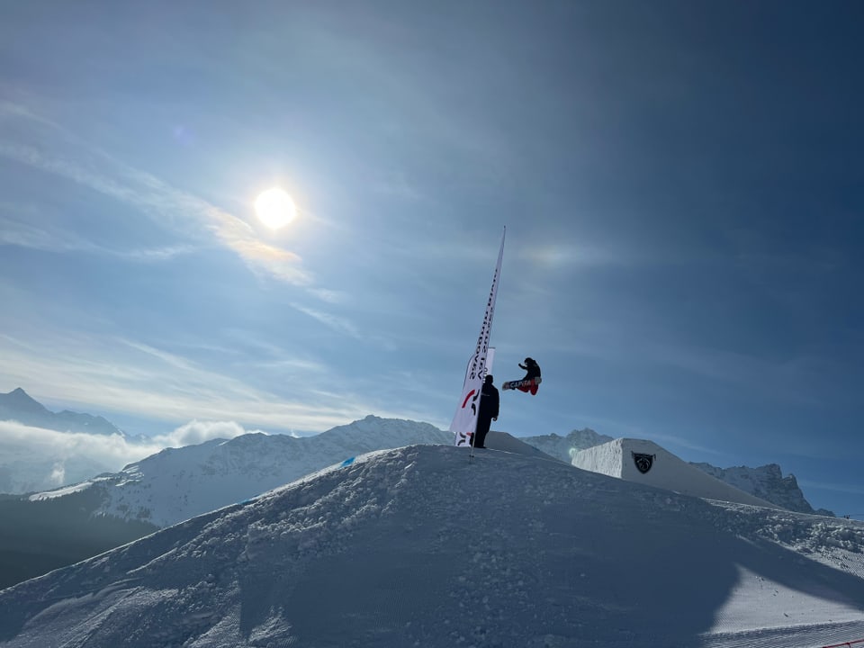 Snowboarder springt über eine Schanze.