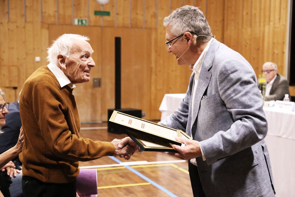 Alexi Decurtins bekommt den Preis vom Präsidenten der SRG.R Vincent Augustin. 