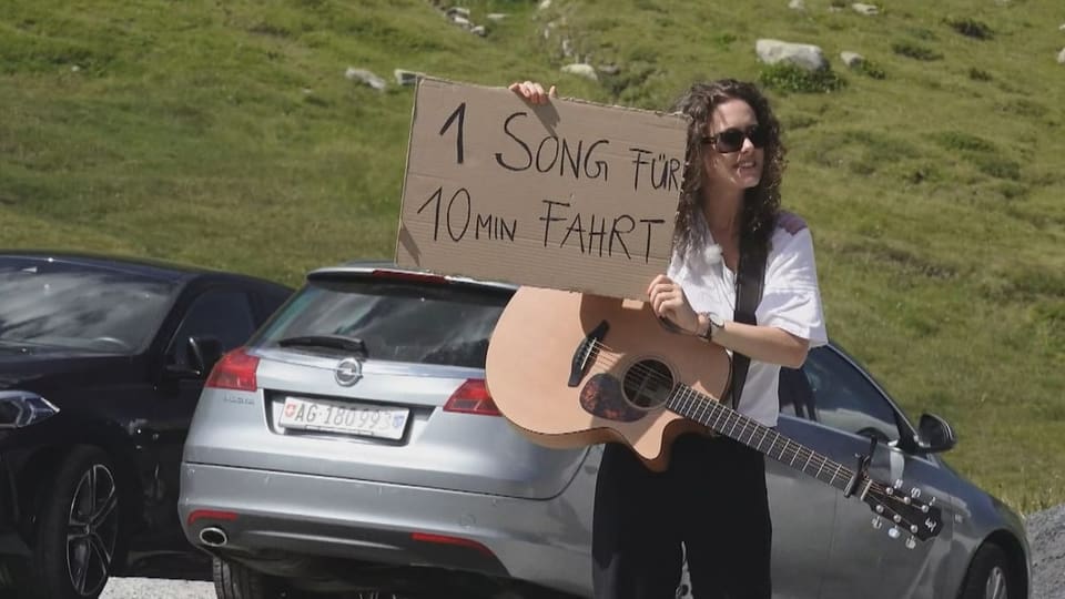 Wer nimmt die musikalische Tramperin mit? Anik Casutt mit einem Schild «1 Song für 10 Min Fahrt»
