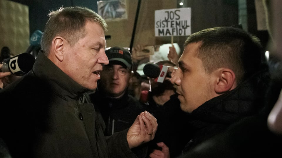 Klaus Iohannis (dretg) en discurs cun in demonstrant sin la Plazza da l'Universitad a Bucarest.