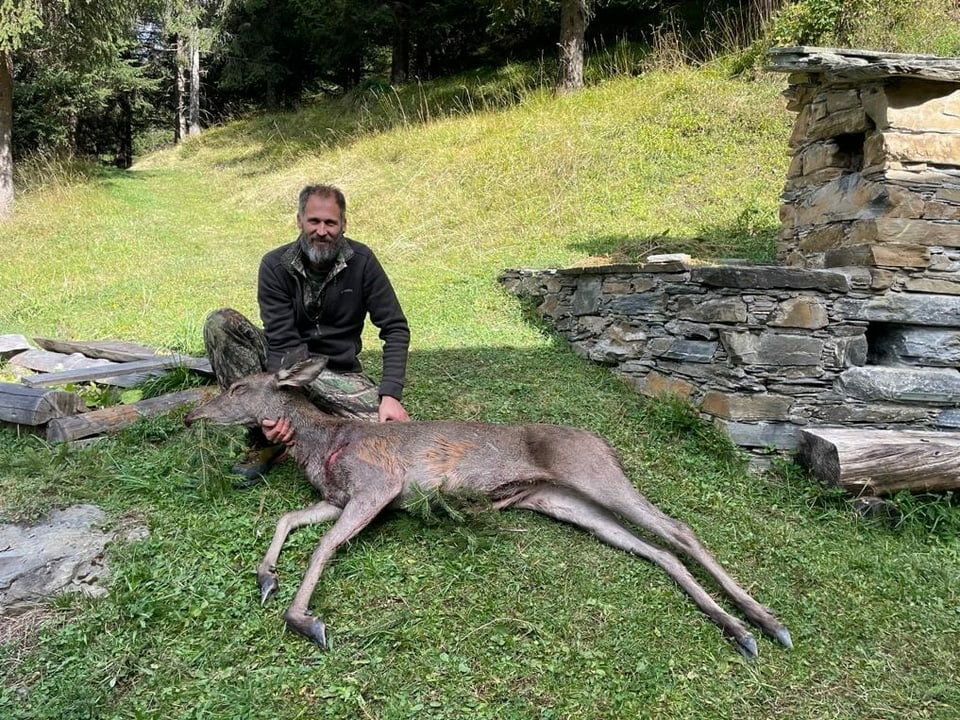 Ein Jäger mit einem geschossenen Hirsch.
