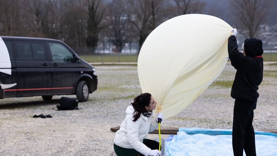 Scolaras da l'Academia Engiadina a suflar si il ballun cun helium