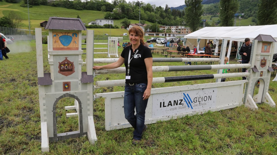 Anastasia Wolf avant igl obstachel da siglir cun chaval  che simbolisescha la porta sura da la cità da Glion