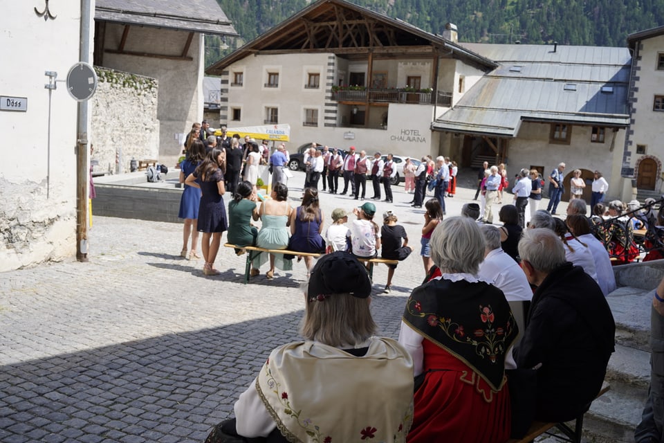 Freies Singen zweier Chöre vor einem grossen Publikum auf dem Dorfplatz inmitten von Müstair.