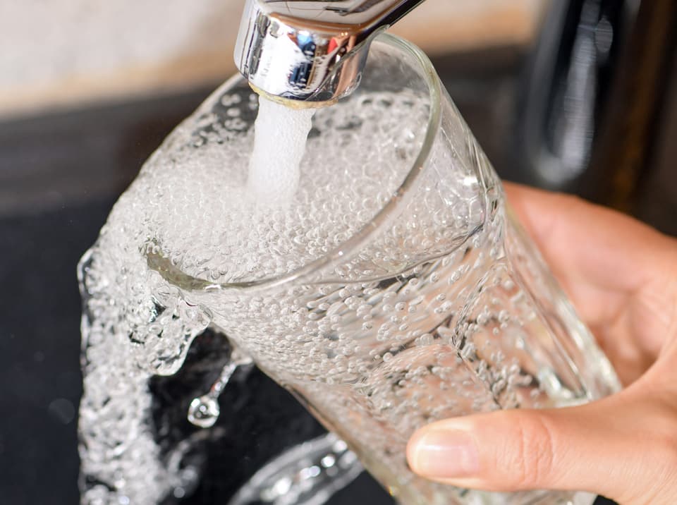 Wasserhahn mit einem Glas Wasser