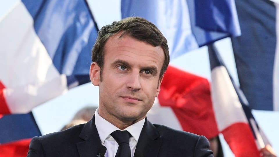 Ina fotografia d'Emmanuel Macron cun bandieras da la Frantscha davosvart.